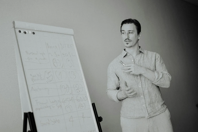 Man standing next to a whiteboard with writing.